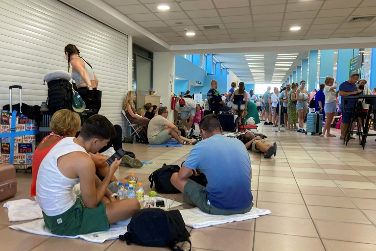 Τουρίστες περιμένουν να απομακρυνθούν από την αίθουσα αναχωρήσεων του διεθνούς αεροδρομίου της Ρόδου στην Ελλάδα στις 23 Ιουλίου 2023 (AFP - Will VASSILOPOULOS)