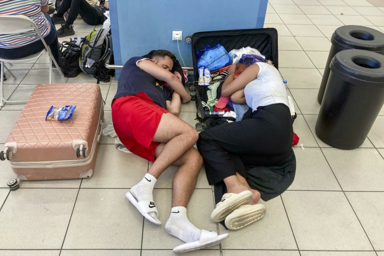 Δύο τουρίστες ξεκουράζονται στο διεθνές αεροδρόμιο της Ρόδου, Ελλάδα, στις 23 Ιουλίου 2023 (AFP - Will VASSILOPOULOS)